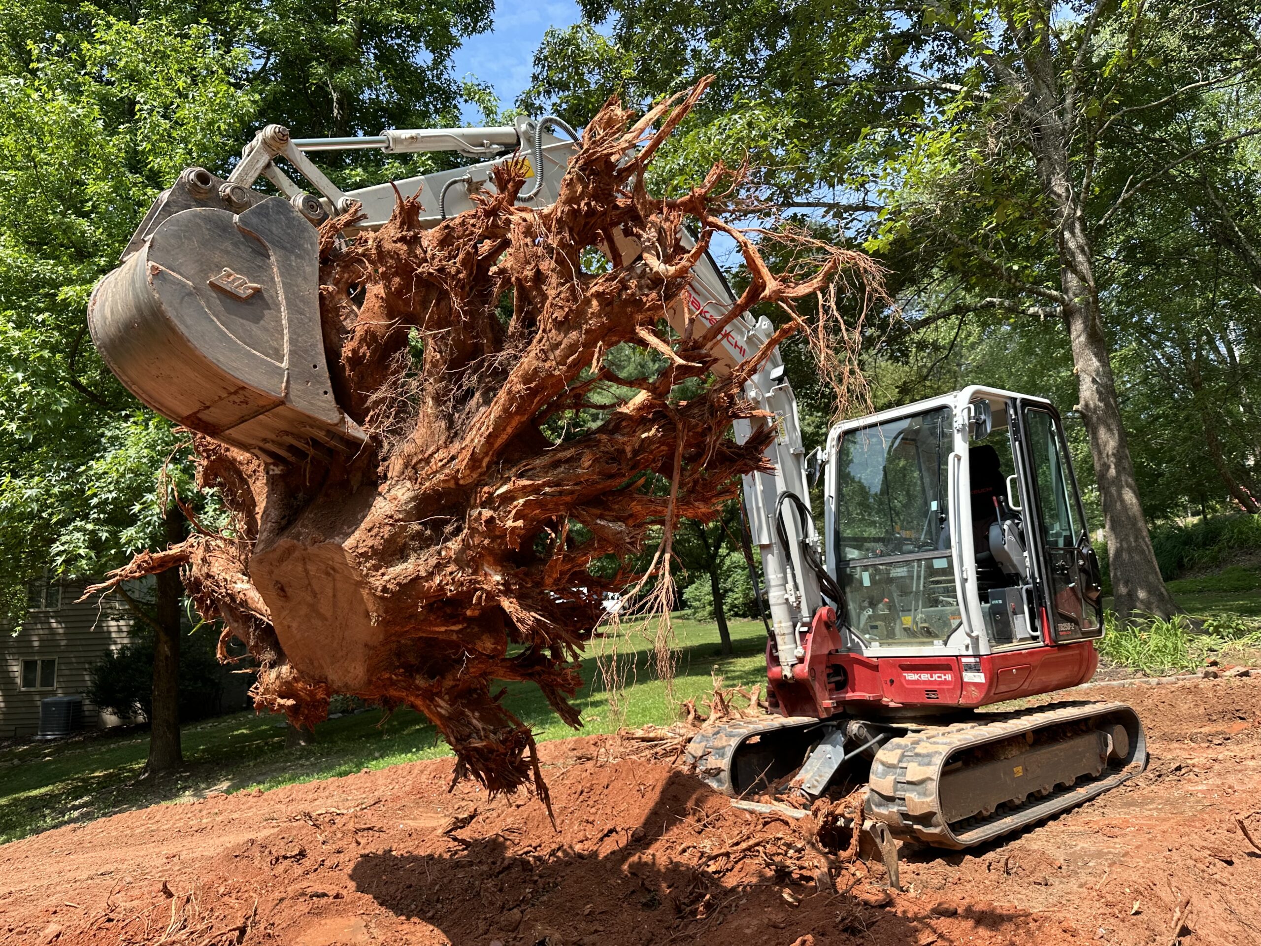 an excavator ripping a stump out of the ground